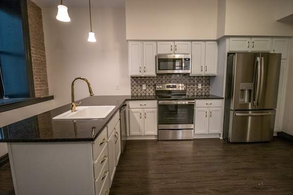 A kitchen with white cabinets and a black countertop.
