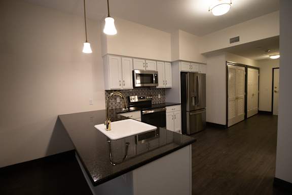 A kitchen with a black counter top and white cabinets.