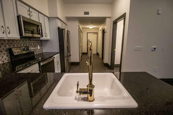 A kitchen with a sink and a black granite counter top.