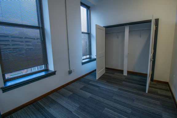 a bedroom with two windows and a closet with two doors