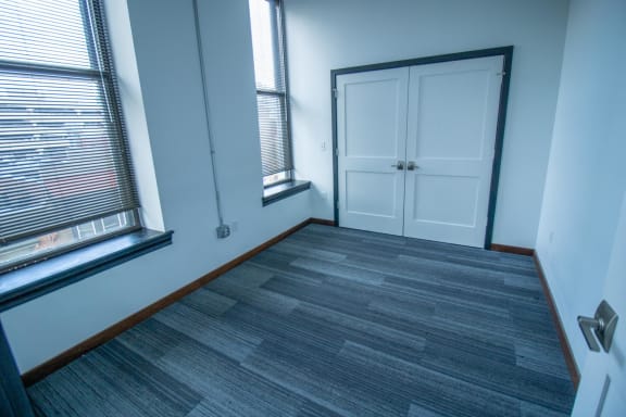 an empty room with a door and two windows