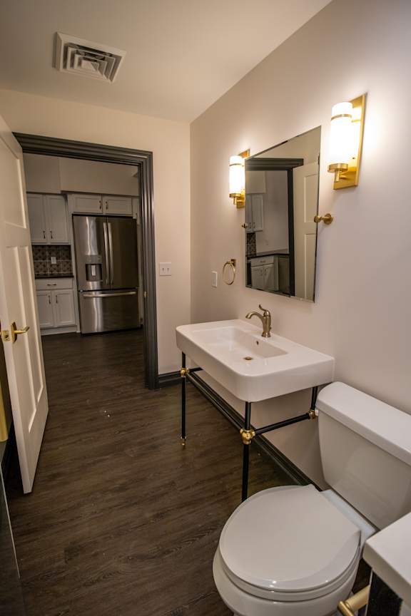 A bathroom with a toilet, sink, and mirror.