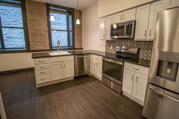 A kitchen with stainless steel appliances and wooden floors.