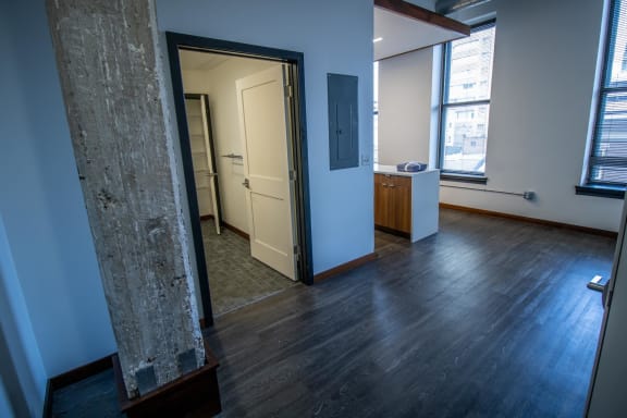 an empty living room with wood floors and a door to a bathroom