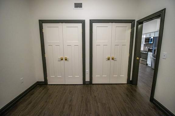 A room with two white doors and a mirror on the right.