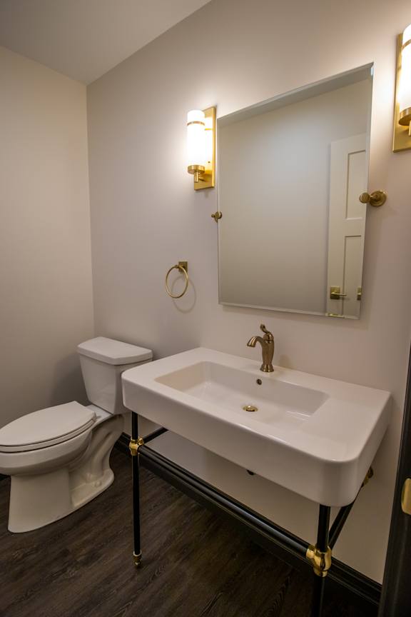 A white sink in a bathroom with a toilet and a mirror.