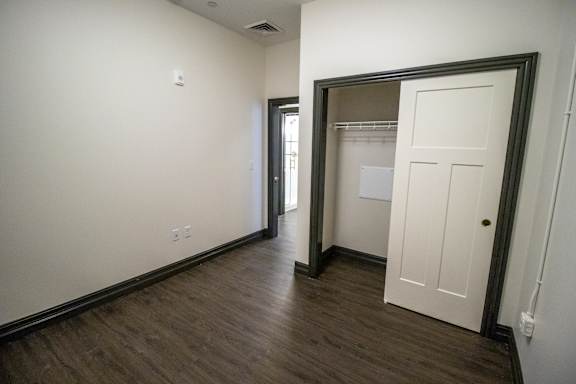 A room with a white door and a wooden floor.