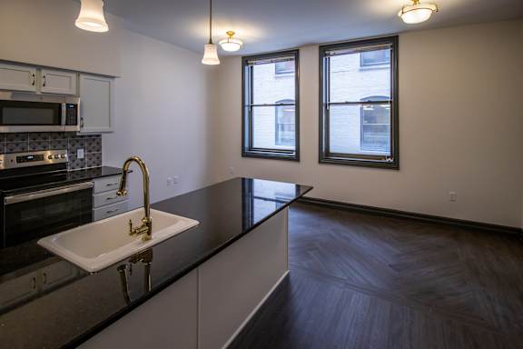 A kitchen with a black counter top and a white sink.