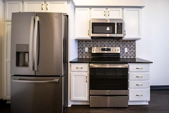 A modern kitchen with a stainless steel refrigerator and a black and white backsplash.