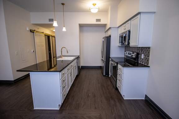 A kitchen with white cabinets and black countertops.