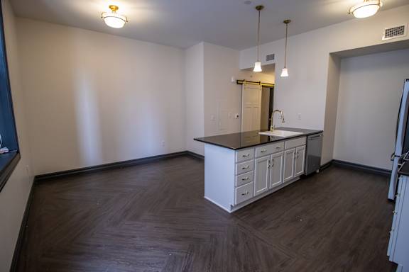 A kitchen with white cabinets and a wooden floor.