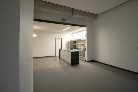 an empty room with a kitchen and a counter in the middle