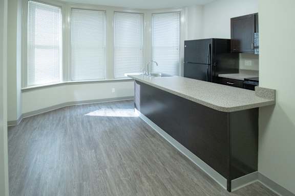 A kitchen with a black refrigerator and a counter top.