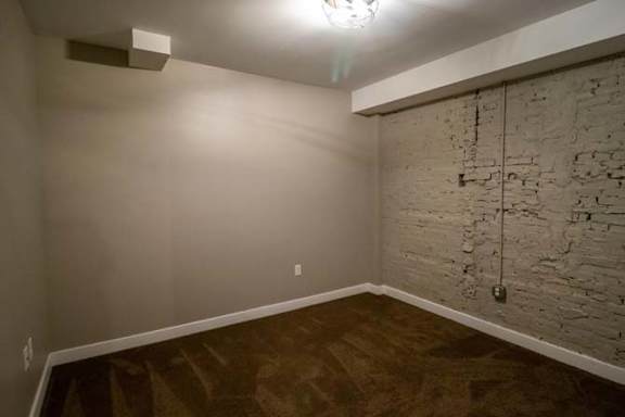 a empty room with a brick wall and wooden floors