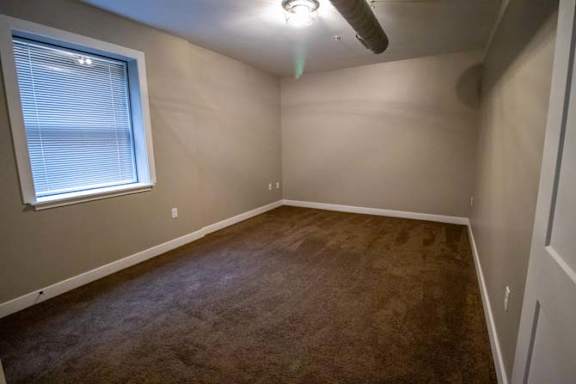 an empty room with a window and a ceiling fan