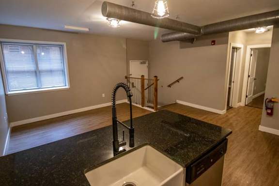 an empty living room with a sink in a kitchen