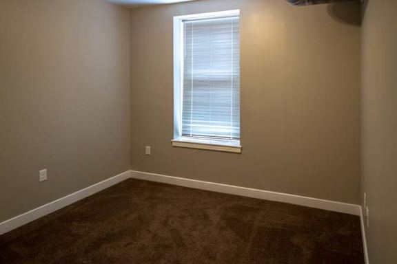 a empty room with a window and brown carpet