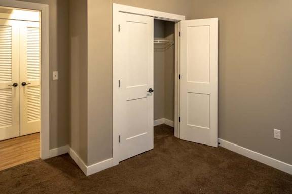 an empty room with a closet and two doors