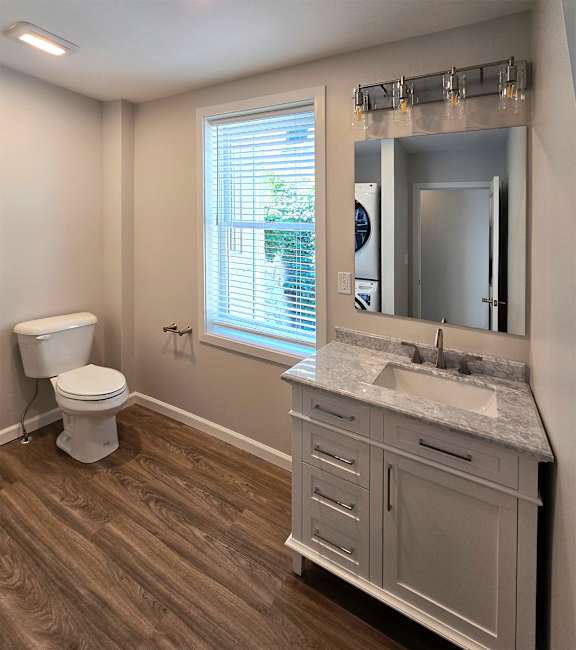 A bathroom with a toilet, sink, and mirror.