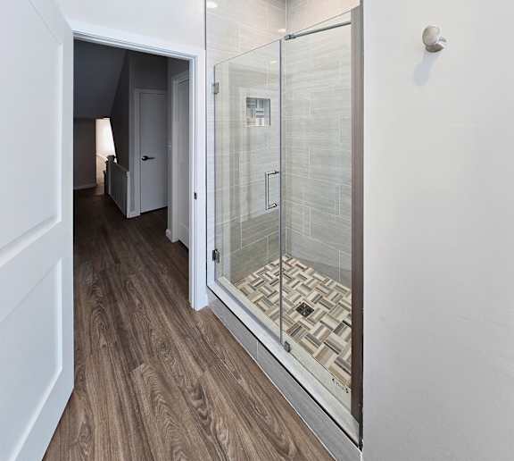 A bathroom with a walk-in shower and a wooden floor.