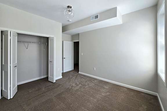 A room with a carpeted floor and a closet with a white door.