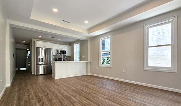 A spacious kitchen with wood flooring and a refrigerator.