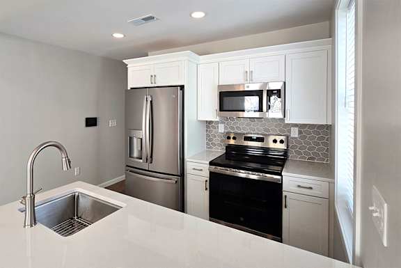 A modern kitchen with white cabinets and stainless steel appliances.