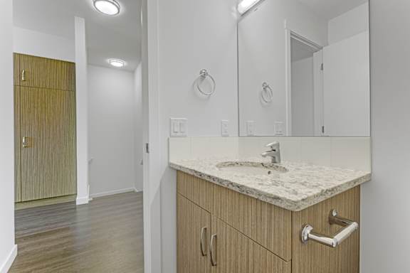 A bathroom with a sink, mirror, and wooden cabinet.
