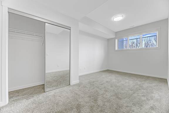 A spacious room with a carpeted floor and a large mirror on the wall.