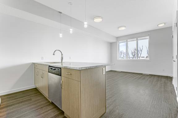 A modern kitchen with wooden cabinets and a marble countertop.