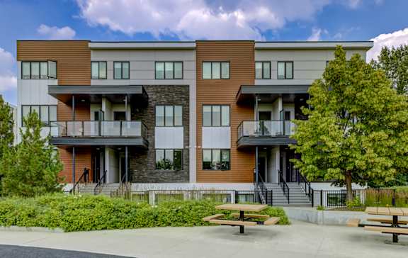 A modern apartment building with a parking lot in front.