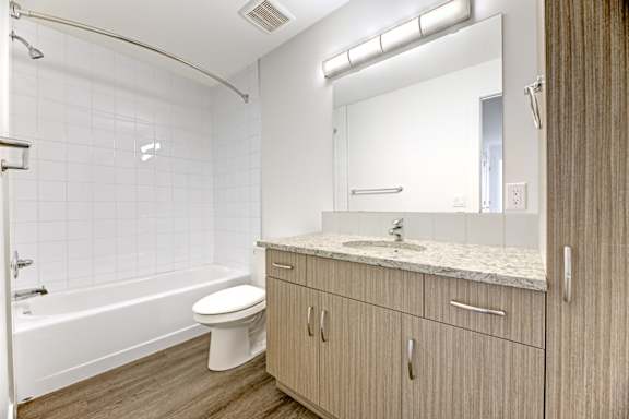 A white tiled bathroom with a toilet, sink, and bathtub.