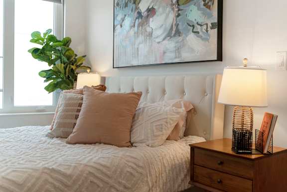 a bedroom with a bed with pillows and a painting above it