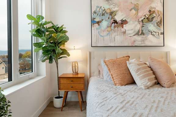 a bedroom with a bed and a potted plant next to a window