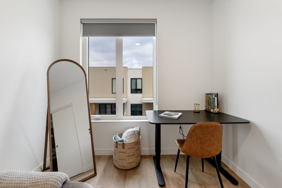 a desk and a mirror in a room with a window