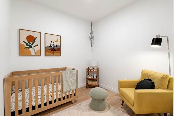 a baby room with a crib and a yellow couch and a chair