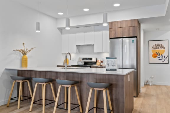 a kitchen with white cabinets and a large island with three stools