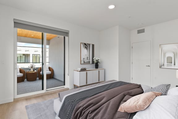a bedroom with a large bed and a sliding glass door to a patio