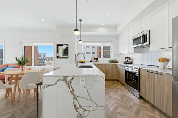 A modern kitchen with a marble island and wooden floors.