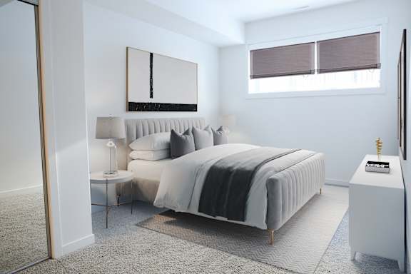 A bedroom with a large bed and a small table with a lamp on it.