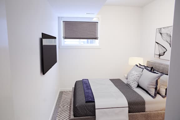 A bedroom with a bed, pillows, and a window.