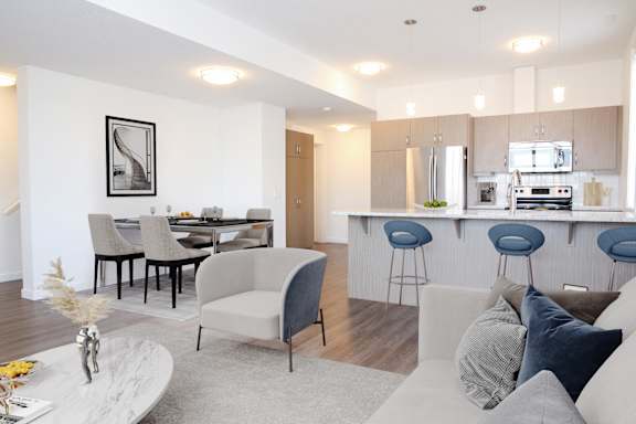 A modern living room with a kitchen in the background.