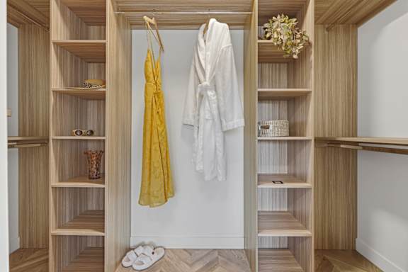 A white robe is hanging on a wooden closet door.