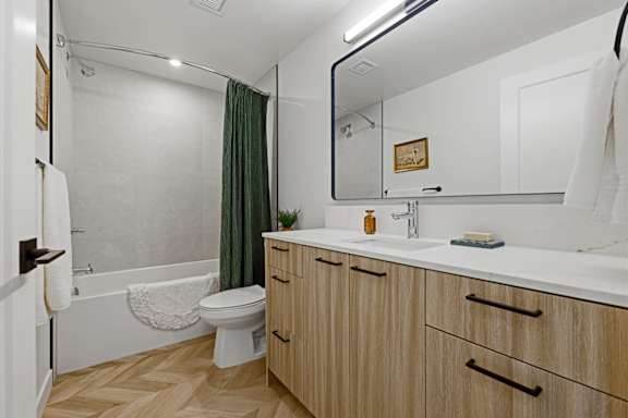 A bathroom with a toilet, sink, and a mirror.