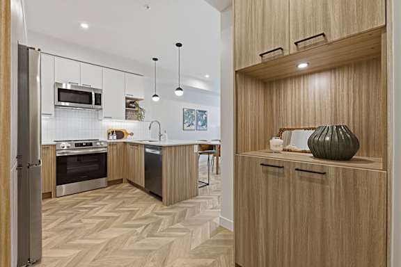 A modern kitchen with wooden cabinets and a herringbone patterned floor.