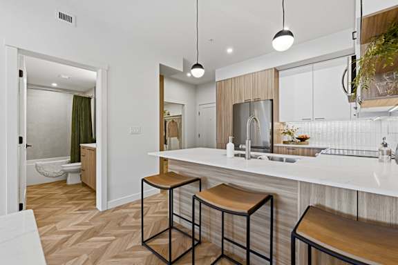 A kitchen with a white counter top and bar stools.
