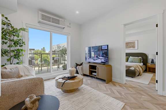 A living room with a flat screen TV and a large window.