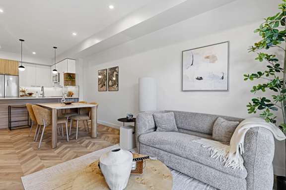 A modern living room with a grey couch and a wooden dining table.