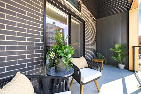 A patio with a black chair and a table with a potted plant on it.