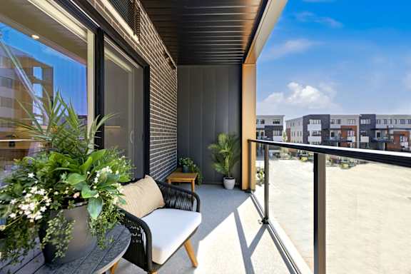 A balcony with a chair and a table with a potted plant on it.